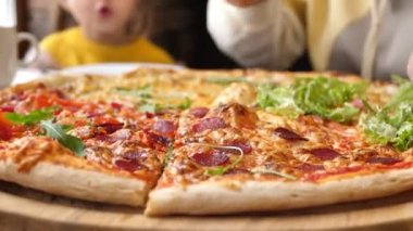 Bir kafedeki ahşap tabaktan pizza alan ellerin yakın çekimi.