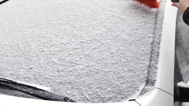 Las manos sostienen y limpian la ventana del auto de la nieve. coche cubierto de nieve durante las fuertes nevadas — Vídeos de Stock