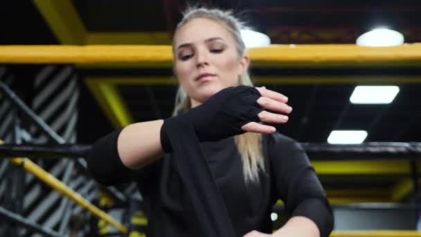 Female boxer ties her hands with a black bandage before training. — Stock Video