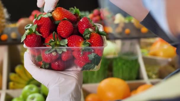 Großaufnahme von Erdbeeren in einem Tablett in den Händen eines Verkäufers mit Handschuhen und Maske während der Quarantäne — Stockvideo