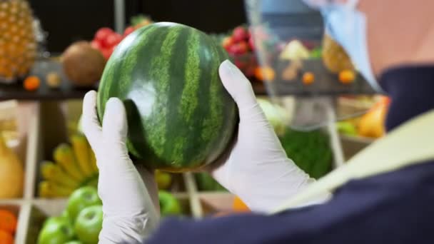 Крупный план арбуза в руках продавца овощей в перчатках во время карантина — стоковое видео