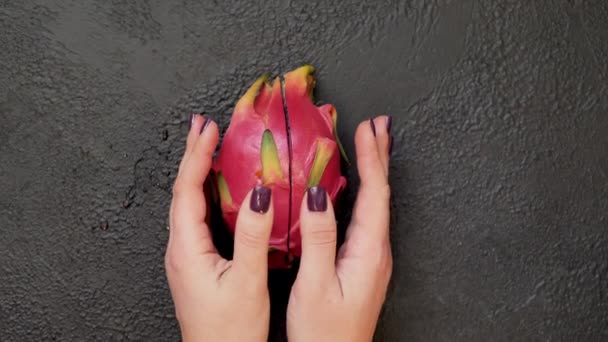 Close-up de mãos quebrando uma fruta pitahaya ao meio em um fundo preto — Vídeo de Stock