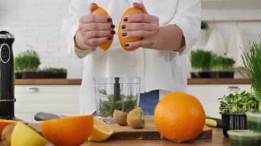 Buğday suyu kokteyli yapmak için portakal suyu sıkan bir kadının yakın çekimi. witgrass, sağlıklı yiyecek.