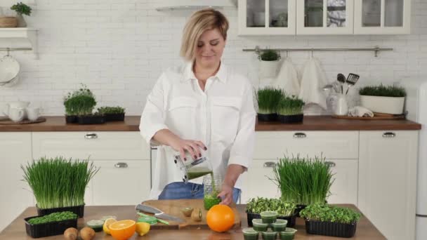 Mujer joven vierte un cóctel de frutas y verduras con hierba de bruja en un frasco con una paja — Vídeos de Stock