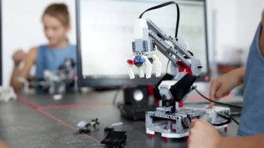 Akıllı okul çocuğu masada oturuyor ve bir okul dersinde robot cihaz yapıyor..