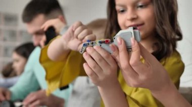 Okuldaki bir anne ve kızın el resimleri. İnşaat setinden kontrol edilen bir robot yapıyorlar.