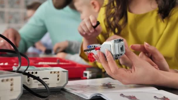 Gros plan d'une mère et de ses filles à l'école fabriquant un robot commandé à partir d'un kit de construction — Video