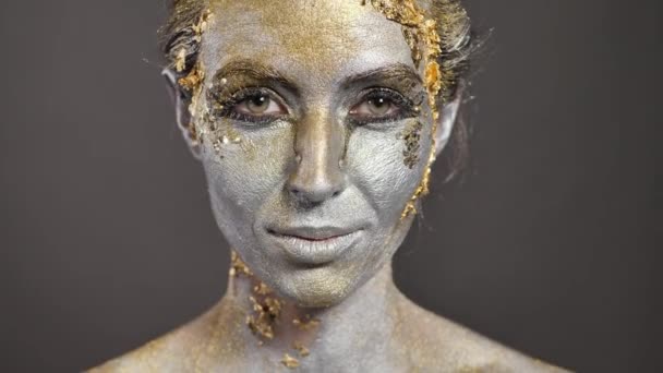 Hermosa joven modelo femenina con pintura dorada y plateada en su piel y cabello en el estudio — Vídeo de stock