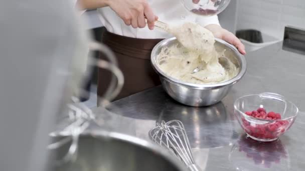 Professional pastry chef prepares a cake in the kitchen and adds berries to the sponge dough — Stock Video