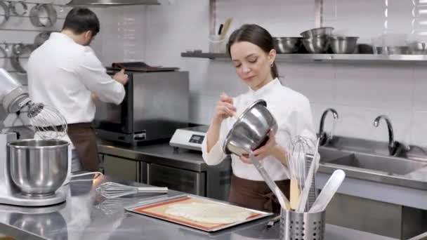 Pastelera mujer chef vierte la masa en una bandeja para hornear con pergamino — Vídeos de Stock