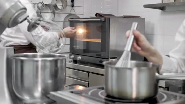 Manlig konditor kontrollerar beredskapen av svampdegen i ugnen i ett professionellt kök — Stockvideo