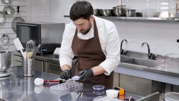 Ο σεφ ζαχαροπλαστικής κάνει σχέδια από condurine σε καραμέλες σοκολάτας — Αρχείο Βίντεο
