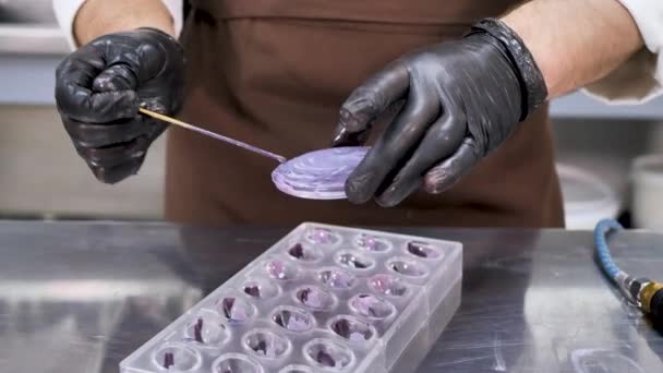 Man pastry chef makes drawings of condurine on chocolate candies — Stock Video