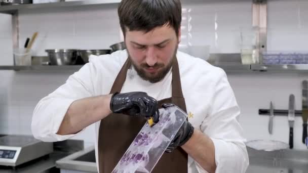 Çikolata küreleri için bir kalıba parlak kandurin sürmek için bez kullanan erkek pasta şefi. — Stok video