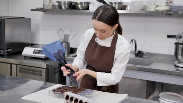 Çikolatacı çikolatayı kalıplara döküyor. Pasta poşeti şefi erimiş çikolatayı silikon kalıba dolduruyor. — Stok video