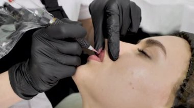 Bir kozmetolog güzellik salonundaki dudaklara kalıcı makyaj uygular. Dövme