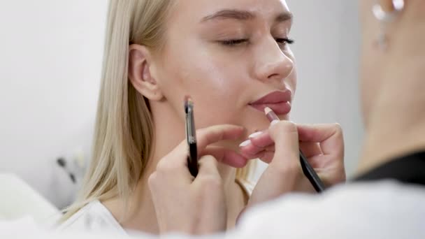 Maquiagem nos lábios. Close-up de um cosmetologista pintando os lábios com um lápis antes da maquiagem permanente — Vídeo de Stock