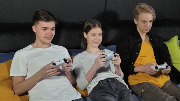 Група друзів підлітків, хлопчиків і дівчаток грають у відеоігри на консолі в ігровому клубі — стокове відео