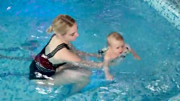 Ung mor, svømmelærer og lykkelig liten jente i bassenget. Lærer spedbarn å svømme. – stockvideo