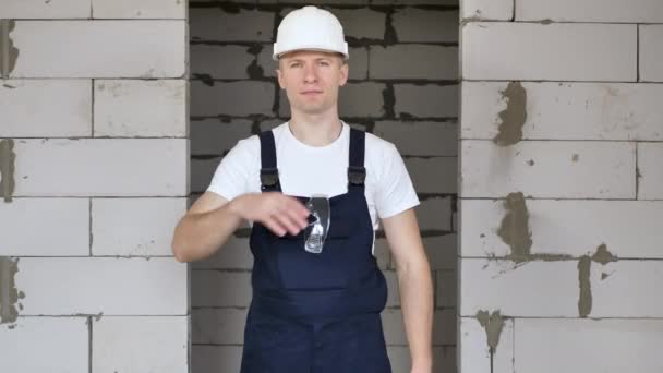 Мужчина строитель в каске надевает защитные очки — стоковое видео