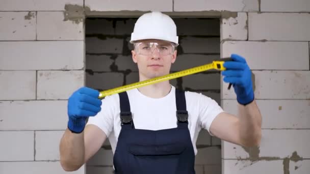 Portret pracownika budowlanego w kasku trzymającego koło ruletki — Wideo stockowe