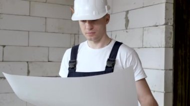 Mimarın portresi. Mimarların yerleşim planı üzerinde çalışıyor. İnşaat alanındaki belgelerle çalışıyor ve telefonda konuşuyor.