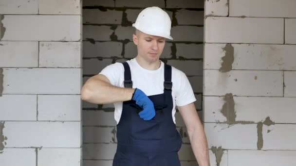 Retrato de um arquiteto-construtor estudando o plano de layout das instalações, trabalhando com documentos no canteiro de obras e falando ao telefone — Vídeo de Stock