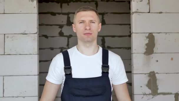 Mužský stavební dělník v modrých rukavicích si nasadí svařovací masku na cihlovou zeď — Stock video