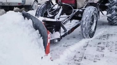 Kürekli bir traktör karı kaldırır. Sabanla belediye yol süpürücüsü.