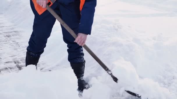 Los empleados de los servicios municipales en una forma especial están limpiando la nieve de la acera con una pala — Vídeo de stock