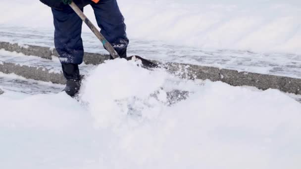 Funcionários de serviços municipais em uma forma especial estão limpando neve da calçada com uma pá — Vídeo de Stock