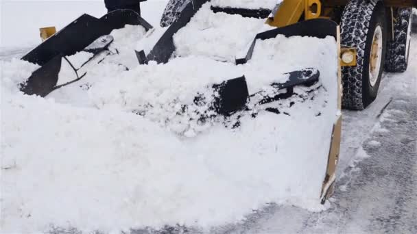 Traktor som rengör vägen från snön. Grävmaskinen rengör gatorna från stora mängder snö i staden — Stockvideo