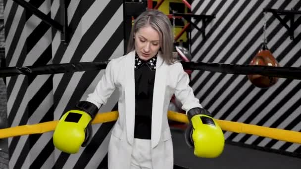 Beyaz takım elbiseli genç bir iş kadını ve boks eldivenleri. — Stok video