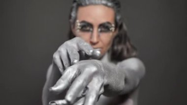 Cildinde ve saçlarında gümüş boya olan güzel bir kadın elinin yakın çekimi.