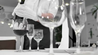 Bir garsonun eli bardağa kırmızı şarap dökerken yakın plan fotoğrafı.