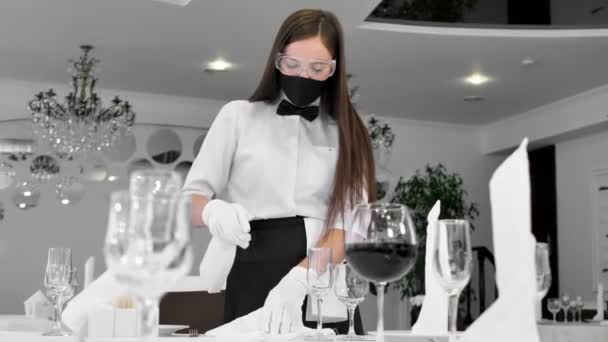 Porträt einer Kellnerin mit Gesichtsmaske und Gesichtsschutz, die während der sozialen Distanzierung einen Tisch in einem Café putzt — Stockvideo