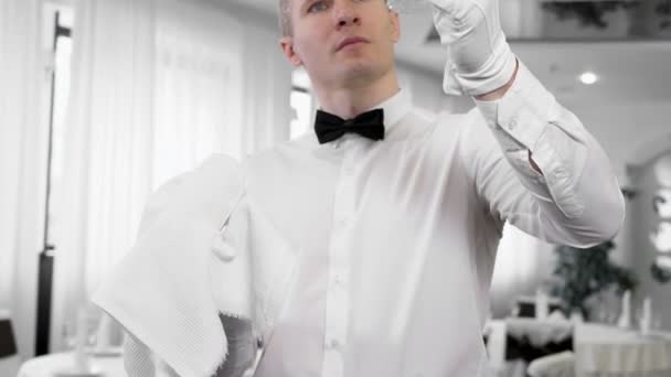 Um garçom macho em luvas brancas limpa um copo de vinho — Vídeo de Stock