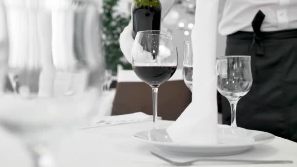 Man servitör i vita handskar häller rött vin i ett glas — Stockvideo