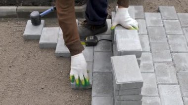 Bir zanaatkar kumun üzerine beton kaldırım taşları serer.