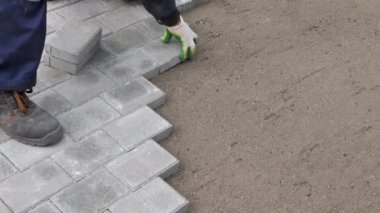 Bir zanaatkar kumun üzerine beton kaldırım taşları serer.
