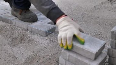 Bir zanaatkar kumun üzerine beton kaldırım taşları serer.
