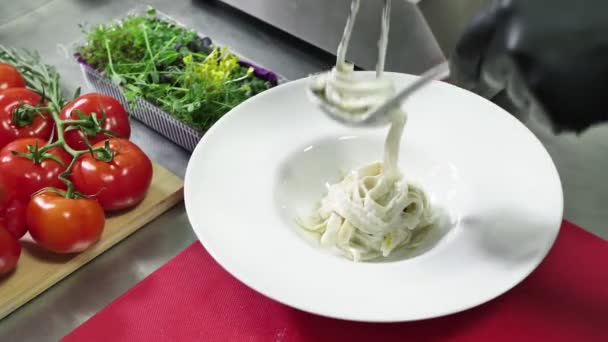 Шеф-повар смещает готовую пасту с кастрюли на тарелку — стоковое видео