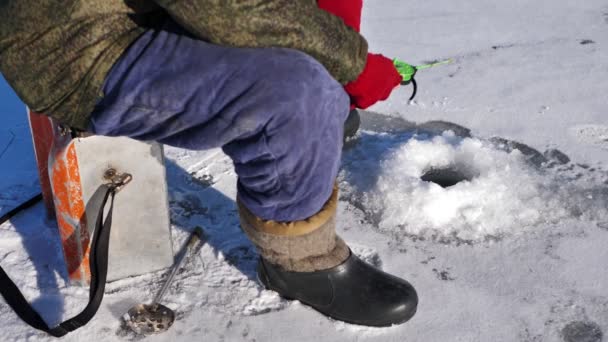 Pesca en hielo en un lago congelado. Un hombre está pescando en un agujero de hielo — Vídeo de stock