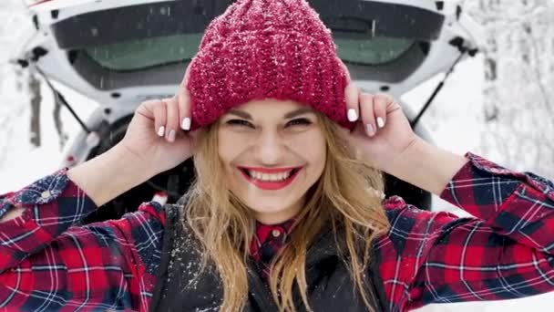 Fiatal nő szórakozik a téli erdőben, piros kalapot húz a szemére és nevet — Stock videók