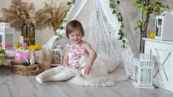 Liten flicka i en vacker klänning stryker en söt vit kanin på påsk semester — Stockvideo