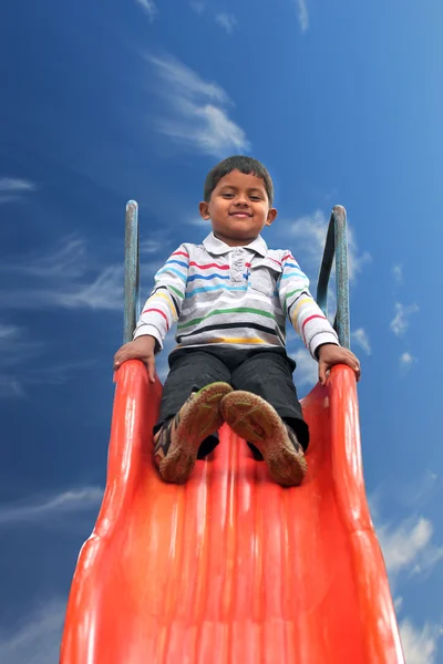 Beautiful smiling(happy) indian boy(kid) on slider in a summer d — Stock Photo, Image