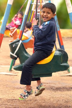 Mutlu bir parkta salıncakta oynarken genç yakışıklı boy(kid) ayarlar