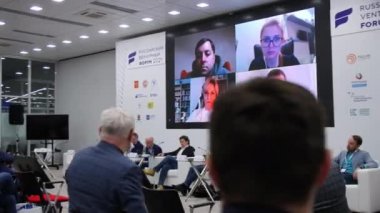 İş konferansında konuşmacılar ekranın altında oturuyorlar