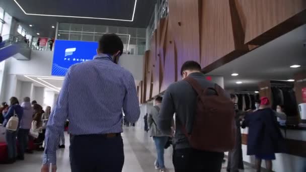 Homem fala por telefone andando com amigo ao longo do corredor de luz — Vídeo de Stock