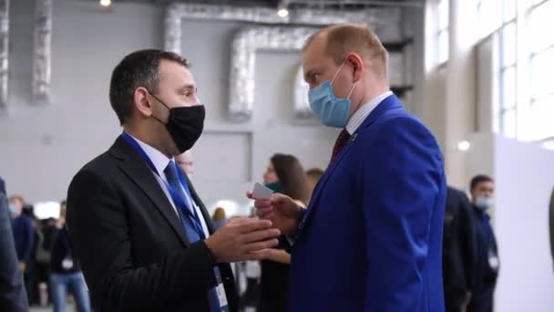 Egy maszkos férfi névjegykártyát tart a kollégájával. — Stock videók